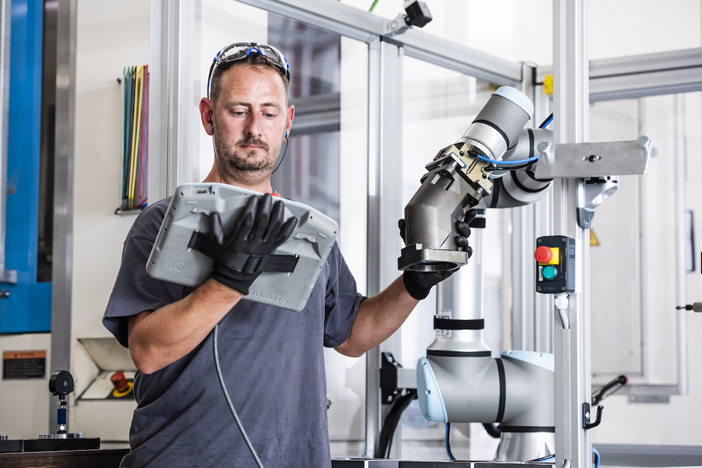 robot in a workshop with a tester next to it
